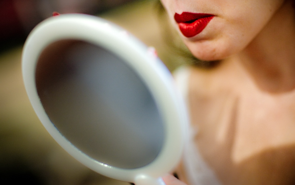 fun close up photo of bride wearing bright red lipstick while looking into a hand mirror - photo by New Mexico based wedding photographers Twin Lens